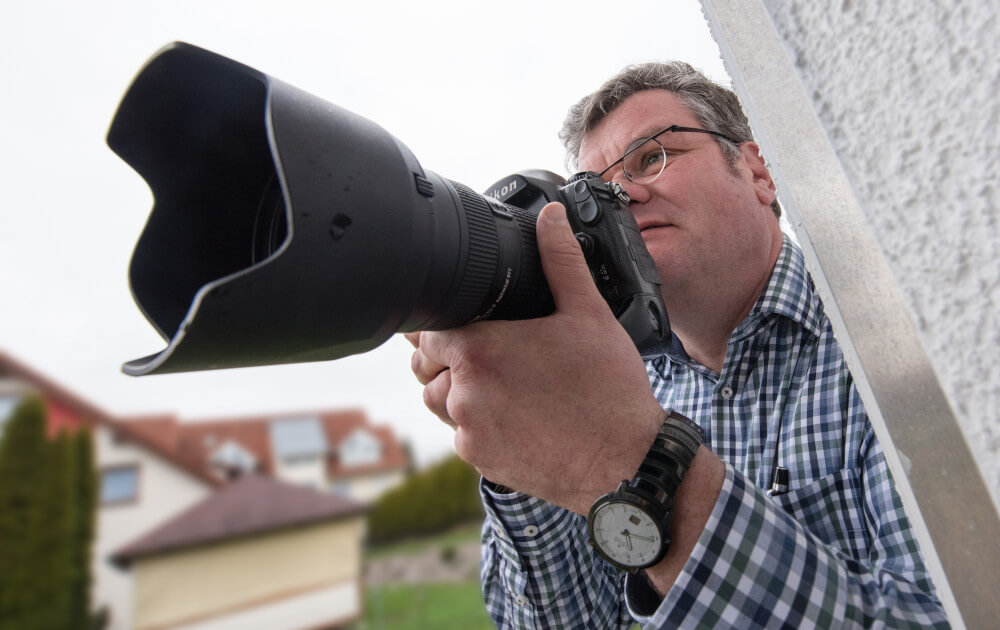 Bild von Michael Hoyer, mit einer Kamera mit großem Objektiv in der Hand